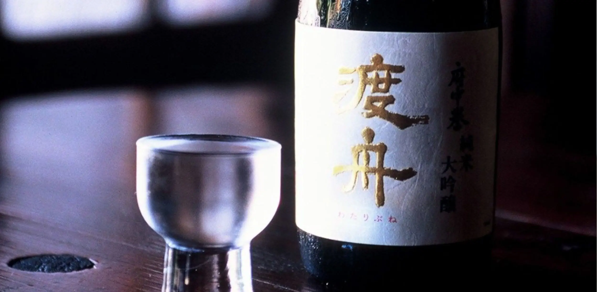 Bottle of sake with glass on wooden table